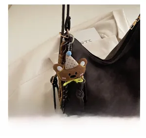 Detail of dark brown pebble leather shoulder bag with a vintage teddy bear plush charm