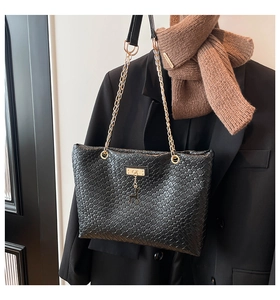 Detailed view of woven bucket bag with gold deer charm and chain on black blazer