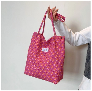 Detailopname van roze bloemen tote bag met geweven merklabel en metalen fittingen