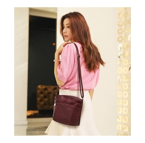 Close-up of a burgundy leather multi-layer bucket bag worn with a casual spring outfit