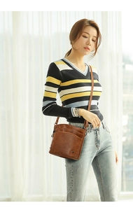 Close-up of brown pebbled leather shoulder bag with multiple zippers and adjustable strap