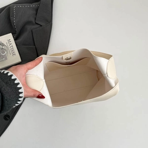 Close-up of beige tote bag interior featuring magnetic closure and stitching details