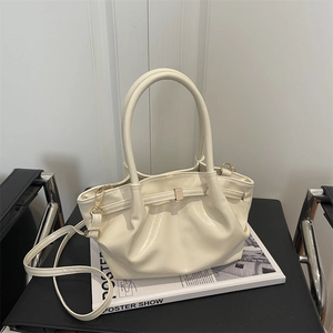 Borsa a secchiello plissettata beige su rivista e sedia in pelle con tracolla