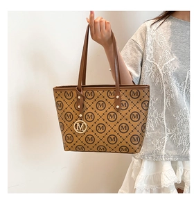 Détail du sac cabas monogramme vintage avec anses en cuir brun et pendentif M doré