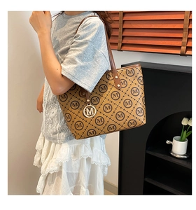 Détail d'un sac cabas marron avec motif monogramme M et pendentif doré en métal M