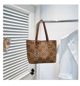 Détail du sac cabas marron avec motif imprimé M et pendentif en métal argenté