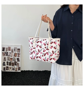 Detalle del bolso tote blanco con estampado de cerezas y remaches metálicos dorados chic