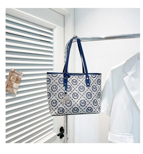Détail du sac cabas en toile monogramme avec motif M et breloque en métal circulaire