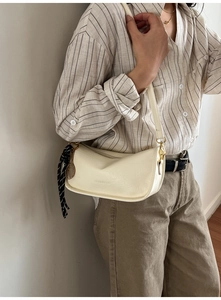 Detail of cream white textured crossbody bag with tennis racket charm and silk scarf