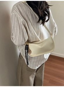 Detail of cream crescent tote bag with tennis racket pendant and striped scarf decoration