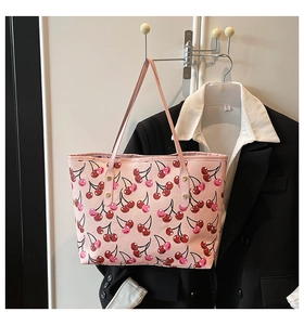 Detalle del bolso tote rosa con estampado de cerezas rojas sobre cuero sintético texturizado