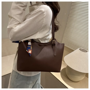 Detail of dark brown tote bag with white stitching and floral silk scarf accessory