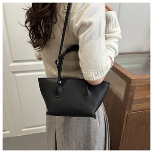 Litchi pattern black bucket bag shown on model highlighting shoulder strap and size