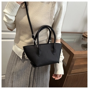 Detail of black lychee grain leather bucket bag shown on model with adjustable strap