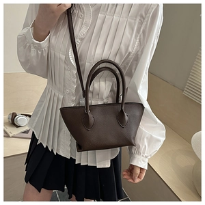 Detail of a dark brown litchi pattern bucket bag shown in a stylish crossbody wear