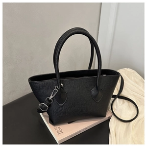 Detail of black lychee texture leather handbag with silver hardware and top handle