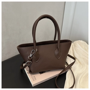 Close-up of dark brown lychee leather bucket bag on pink books with adjustable strap