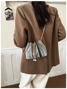 Detail of woven bucket bag with gold chain and white pearl drawstring charms