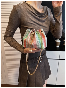 Detail of colorful woven bucket bag with rainbow stripes, pearl charms, and gold chain