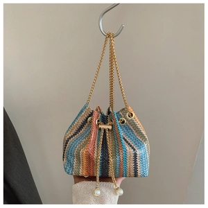 Detail of colorful woven straw bucket bag with gold chain strap and pearl accents