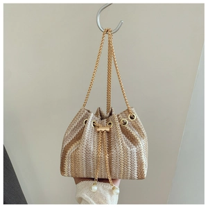 Detail of straw woven bucket bag with beige stripes, chain strap and pearl drawstring