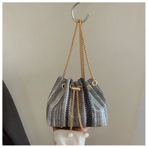 Detail of woven gradient bucket bag with gold chain and large pearl drawstring charms