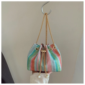 Detail of colorful woven straw bucket bag with gold chain and pearl drawstring charms