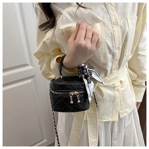 Detail of black quilted mini crossbody bag with gold ball zipper and decorative scarf
