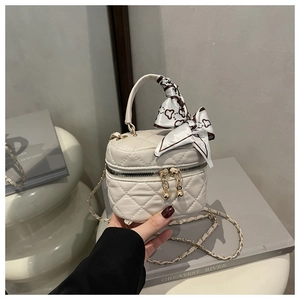 Close-up of white quilted mini bag with golden hardware and silk scarf detail