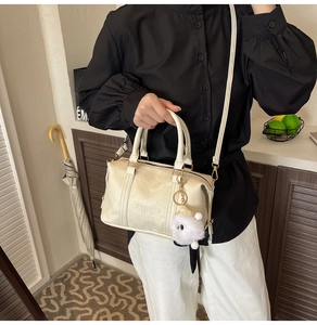 Detail of off-white Boston handbag featuring pleated texture and pompom charm on model