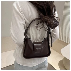 Detail shot of a dark brown French minimalist shoulder bag worn by a model in a bright room