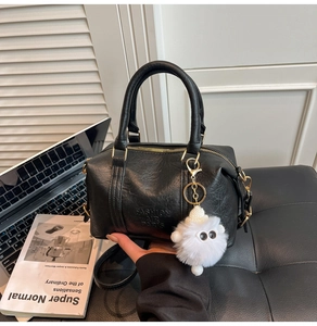 Détail du sac en cuir noir texturé avec zip doré et pendentif peluche blanc