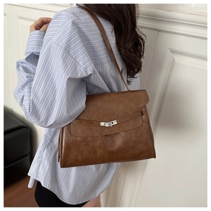 Detail of vintage brown leather tote bag featuring a metallic twist lock and flap closure