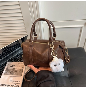 Détail du sac en similicuir marron foncé avec inscription et breloque en peluche