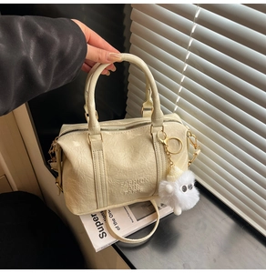 Détail du sac Boston crème plissé avec pompon en fourrure et logo en relief