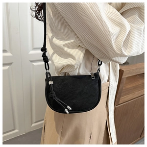 Detail of a vintage matte black saddle bag featuring silver hardware and textured leather