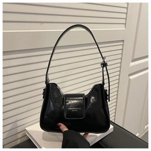 Detail of black glossy crescent shoulder bag with embossed fashion text and smooth leather