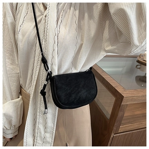 Detail of a matte black saddle crossbody bag featuring a stylish knotted strap design