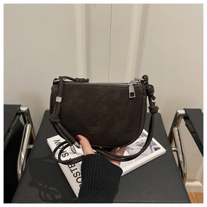 Detail of dark brown matte leather crossbody bag with knot strap and silver hardware