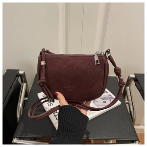 Detail of dark burgundy crossbody bag showing matte texture and knotted shoulder strap