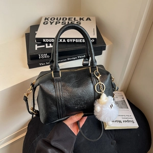 Sac Boston noir en cuir avec poignée supérieure et accessoire de boule de peluche blanche