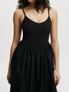 Vestido negro minimalista de tirantes finos con cintura en V y falda plisada a capas