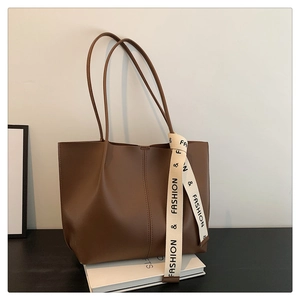 Detail of dark brown matte leather tote bag featuring stylish knit strap decoration