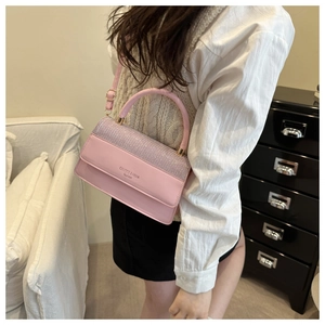 Detailed close-up of pink leather handbag featuring sparkling rhinestone flap and top handle