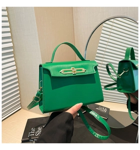 Dettaglio borsa a mano verde brillante strutturata con chiusura dorata e riflesso specchio
