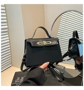 Vista dettagliata della borsa a trapezio nera con chiusura dorata e manico