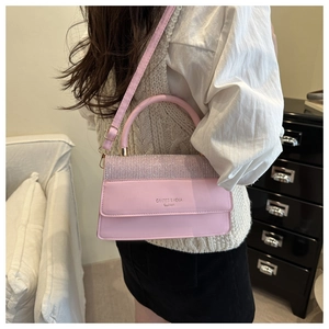 Detail of pink crossbody bag with silver glitter flap and metallic brand lettering