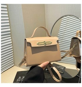 Dettaglio della borsa a trapezio beige con chiusura dorata e tracolla rimovibile