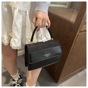 Detail of black leather handbag with glitter patchwork and gold logo lettering