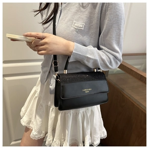 Detail view of black crossbody bag with sequin panel and adjustable leather shoulder strap